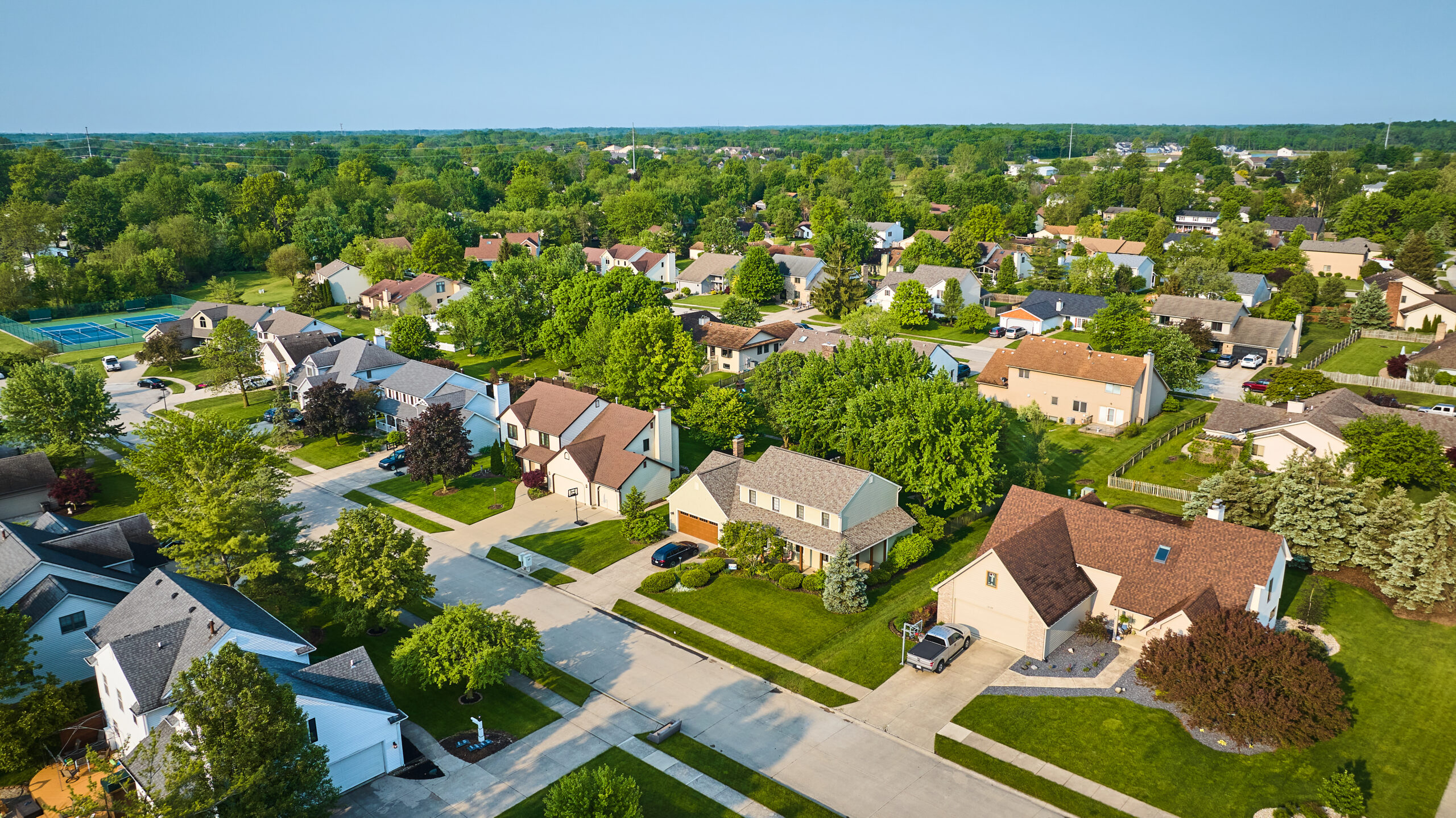 Image of Neighborhood with amenities middleclass houses in summer with tennis court aerial